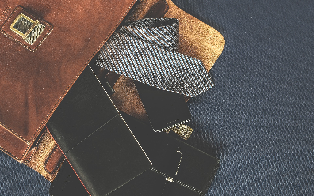 Bild einer alten, ledernen Aktentasche und Business Zubehör wie Stifte und Notizbücher